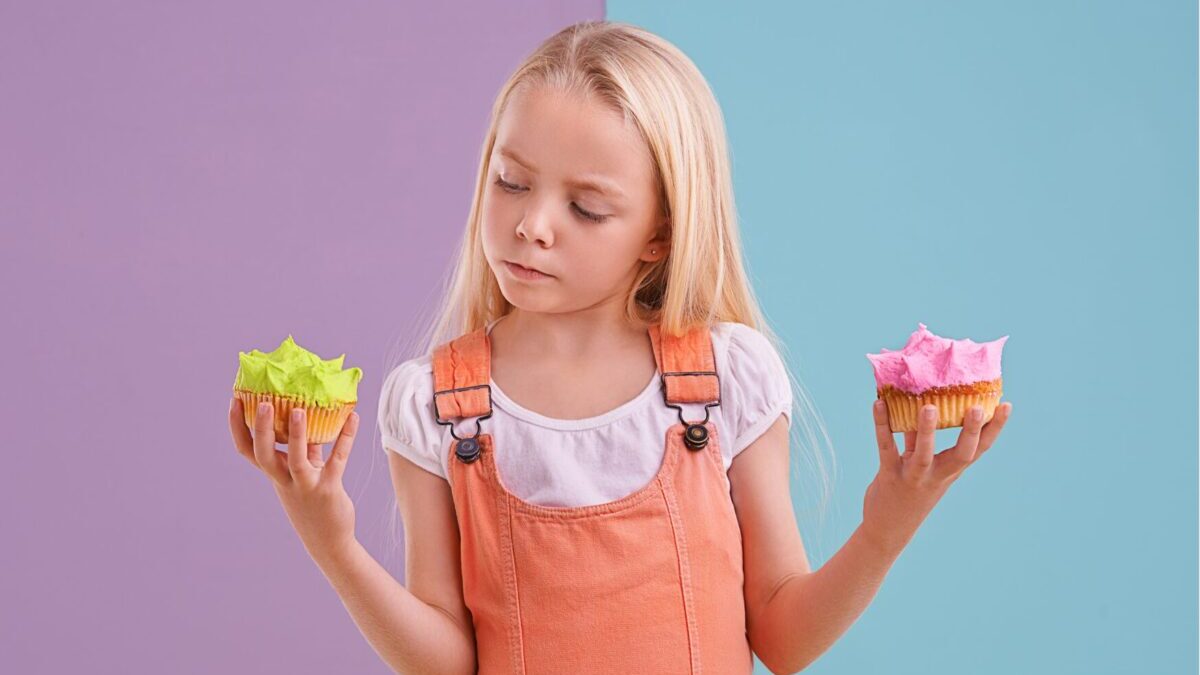ふたつのお菓子を手に持った女の子の画像