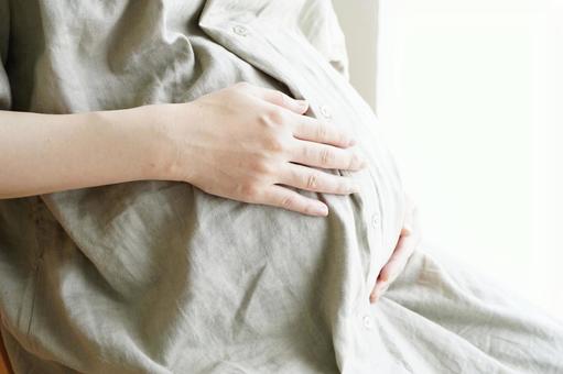 妊婦さんがお腹に手を当てている画像