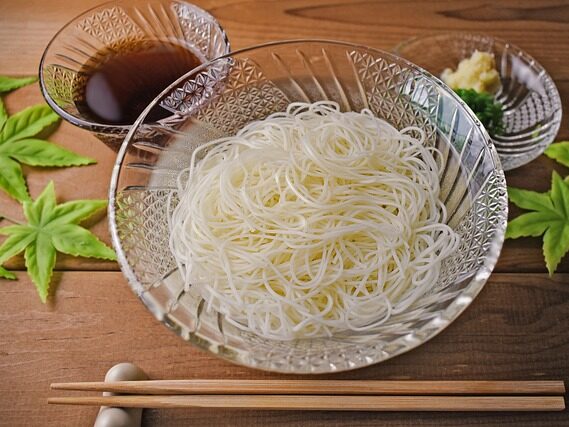 テーブルにそうめん、麺つゆ、薬味、お箸が置いてある画像