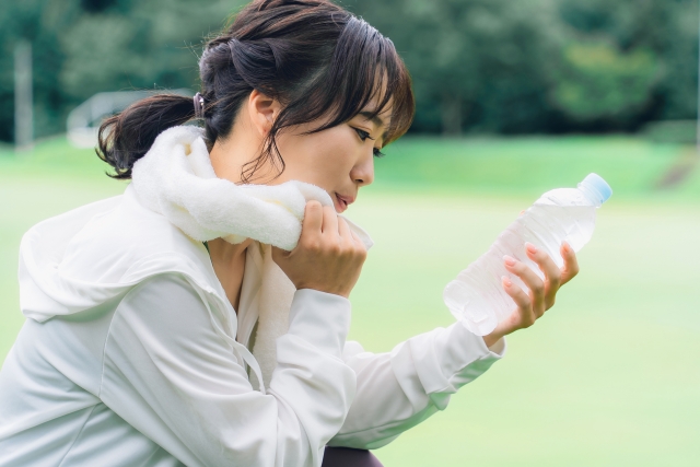 ラベルレスのスポーツドリンクを手に持って眺めている女性の画像