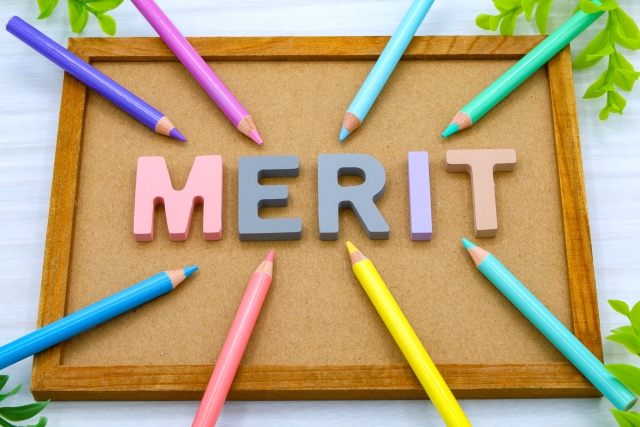「merit」と書かれたブロックの周りに色鉛筆、下に木のボードがある画像。