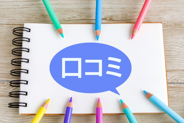 スケッチブックの上に「口コミ」と書かれ、周りに色鉛筆がある画像。